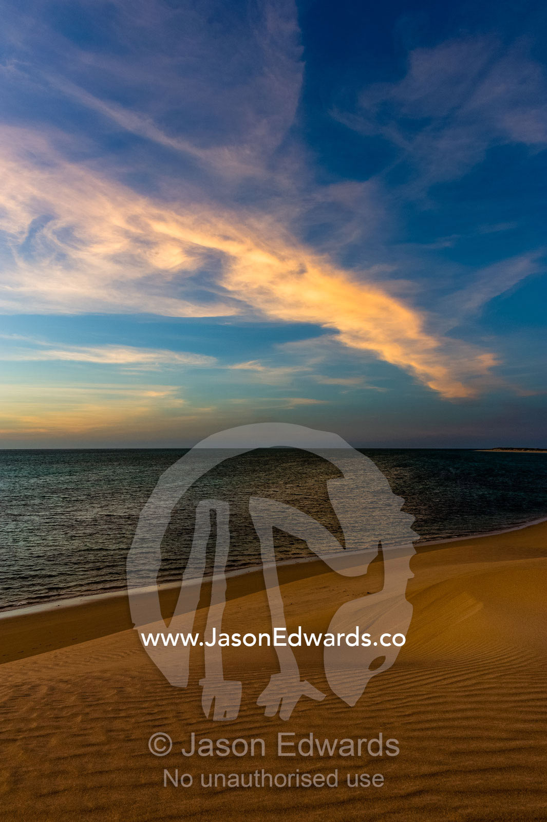 A sunset afterglow casts a pastel hue over a deserted desert beach. Cape Range National Park, Exmouth, Ningaloo Reef, Western Australia, Australia.