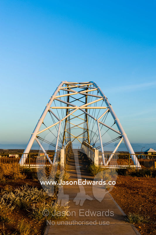 Steel girders of a residential foot bridge arching over a tidal canal. Exmouth, Ningaloo Reef, Western Australia, Australia.