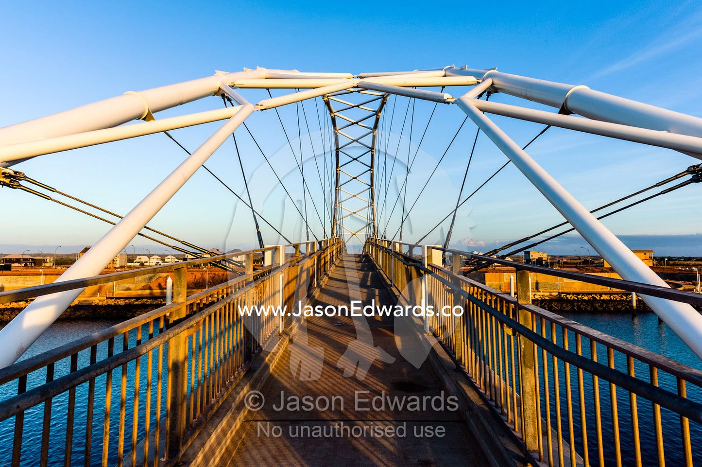 Steel girders of a residential foot bridge arching over a tidal canal. Exmouth, Ningaloo Reef, Western Australia, Australia.