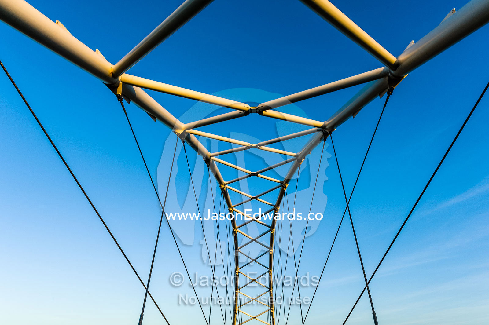 Steel girders of a residential foot bridge arching over a tidal canal. Exmouth, Ningaloo Reef, Western Australia, Australia.