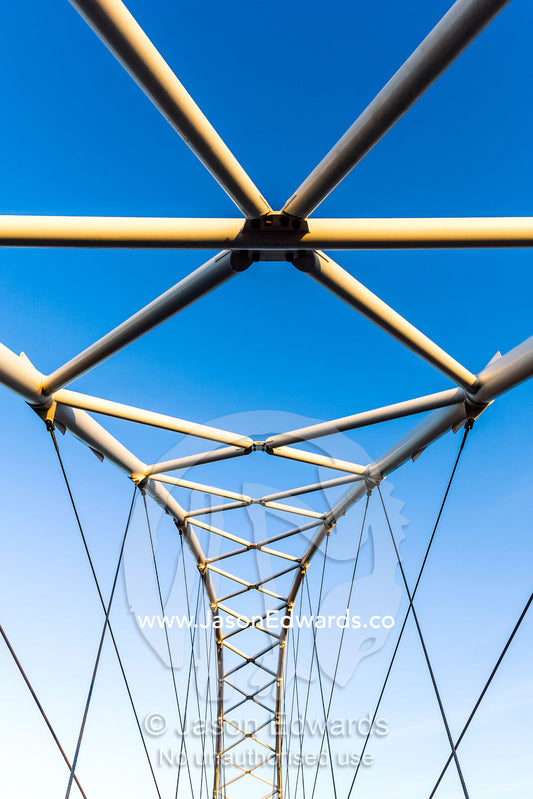 Steel girders of a residential foot bridge arching over a tidal canal. Exmouth, Ningaloo Reef, Western Australia, Australia.