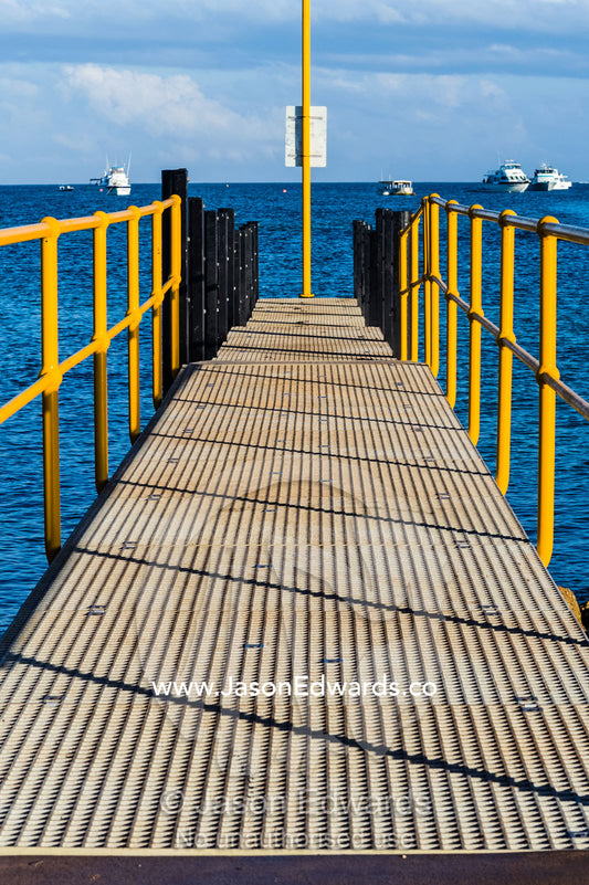 A small jetty with bright yellow safety handrails overlooks the sea. Exmouth, Ningaloo Reef, Western Australia, Australia.