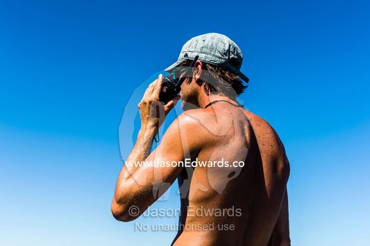 A tanned man talks on a two-way radio from the deck of a boat. Exmouth, Ningaloo Reef, Ningaloo Marine Park, World Heritage Site, Western Australia, Australia.