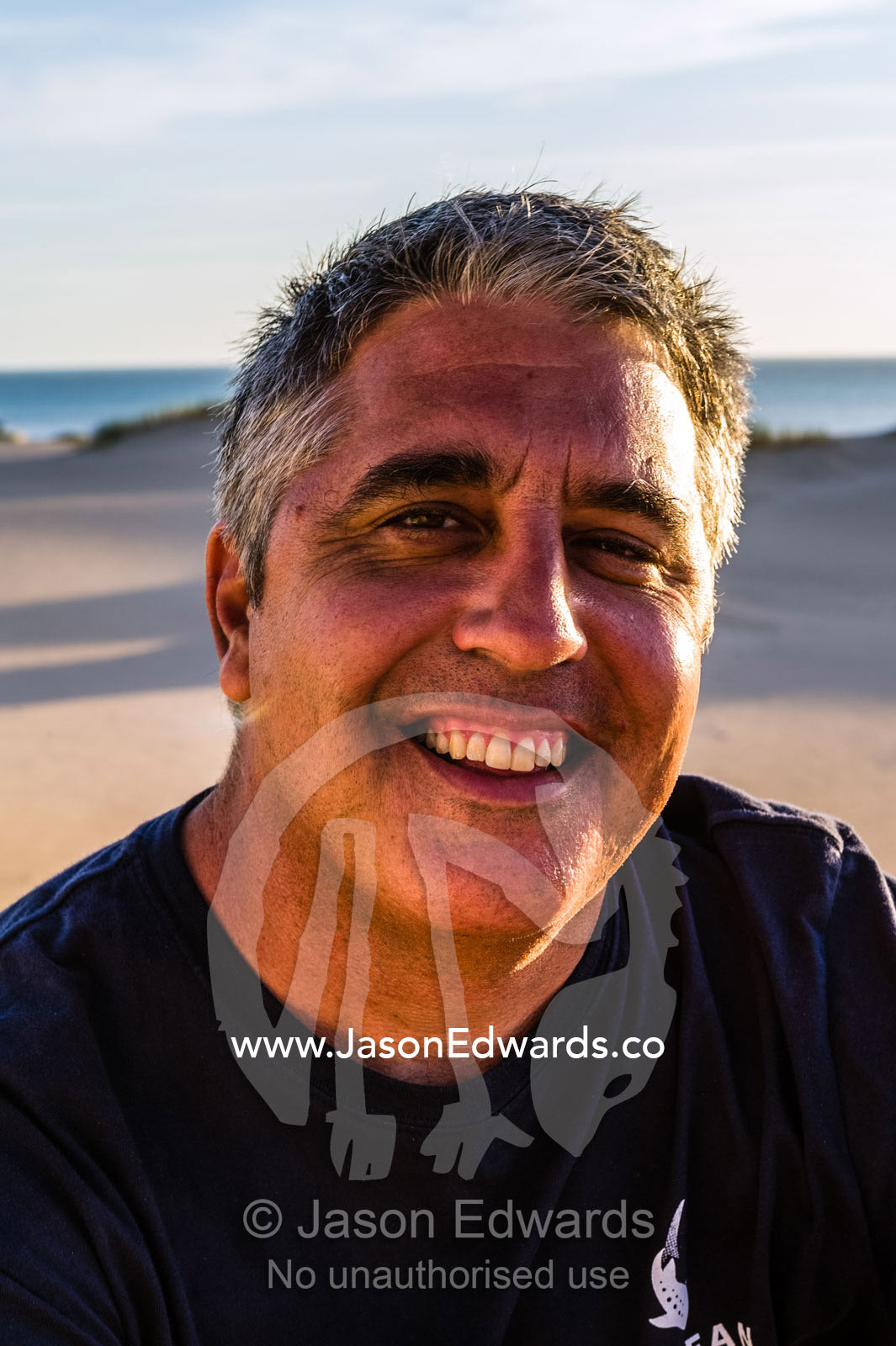 A marine scientist relaxing on an ocean beach at sunset. Cape Range National Part, Exmouth, Ningaloo Reef, Western Australia, Australia.