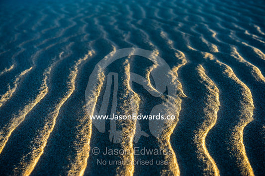 Late afternoon sun rays over windblown ripples on a coastal sand dune. Cape Range National Park, Exmouth, Ningaloo Reef, Western Australia, Australia.