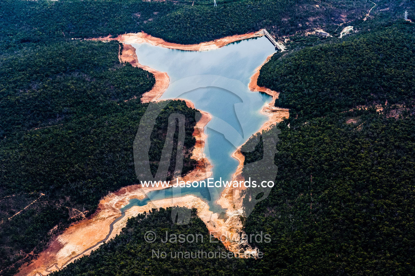 An aerial view of a water storage dam surrounded by forested hills. Perth, Western Australia, Australia.