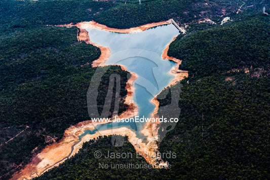 An aerial view of a water storage dam surrounded by forested hills. Perth, Western Australia, Australia.