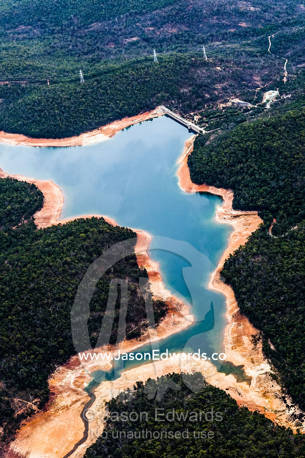An aerial view of a water storage dam surrounded by forested hills. Perth, Western Australia, Australia.