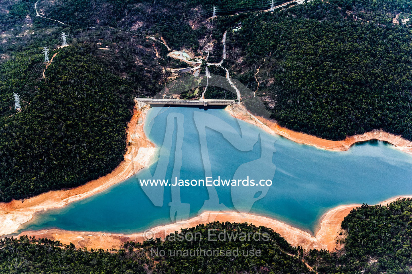 An aerial view of a water storage dam surrounded by forested hills. Perth, Western Australia, Australia.