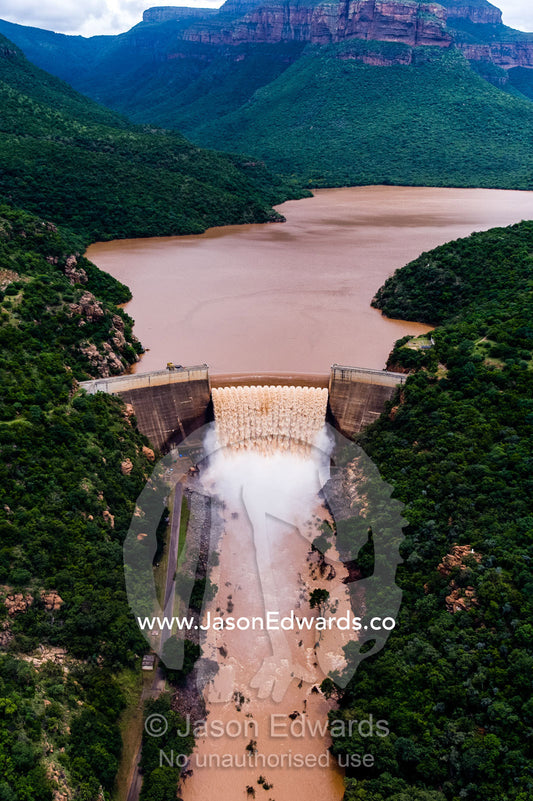 Flood waters cascade over a dam spillway into a torrent of foam. Blyde River Canyon, South Africa.