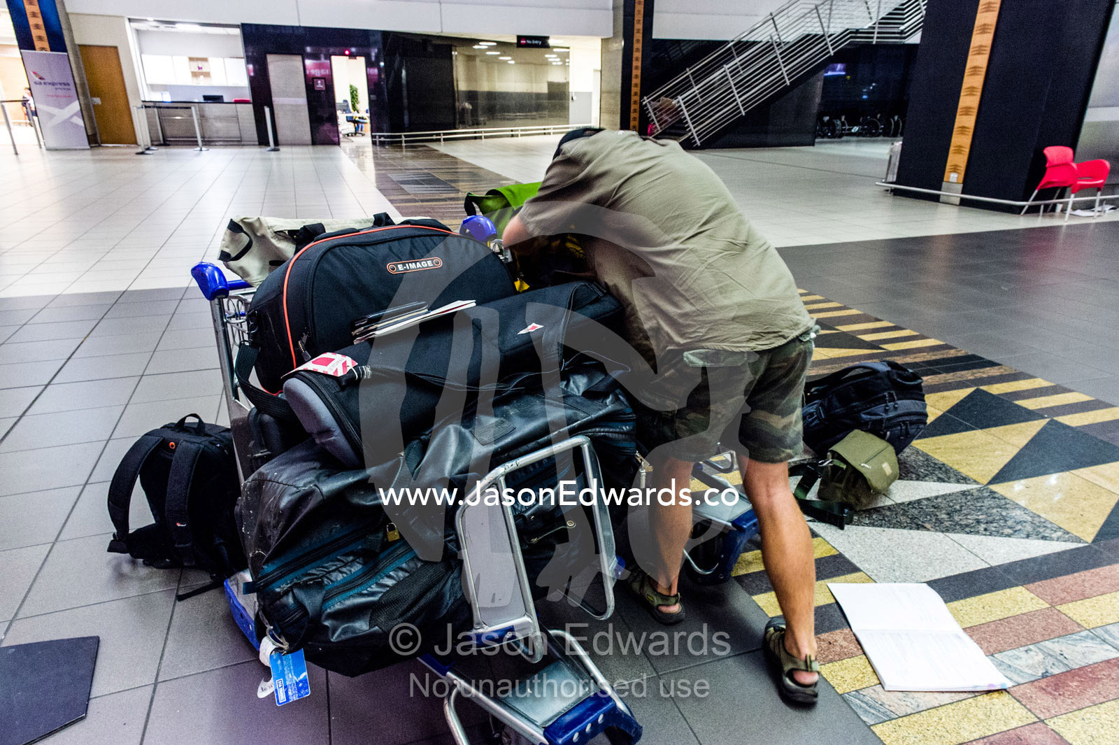 A dejected man waits with his luggage after missing the last flight. Cape Town, Western Cape, South Africa.