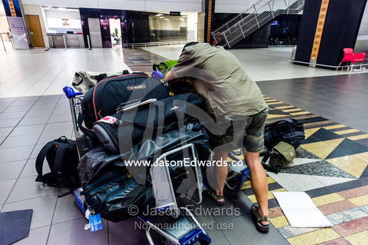 A dejected man waits with his luggage after missing the last flight. Cape Town, Western Cape, South Africa.