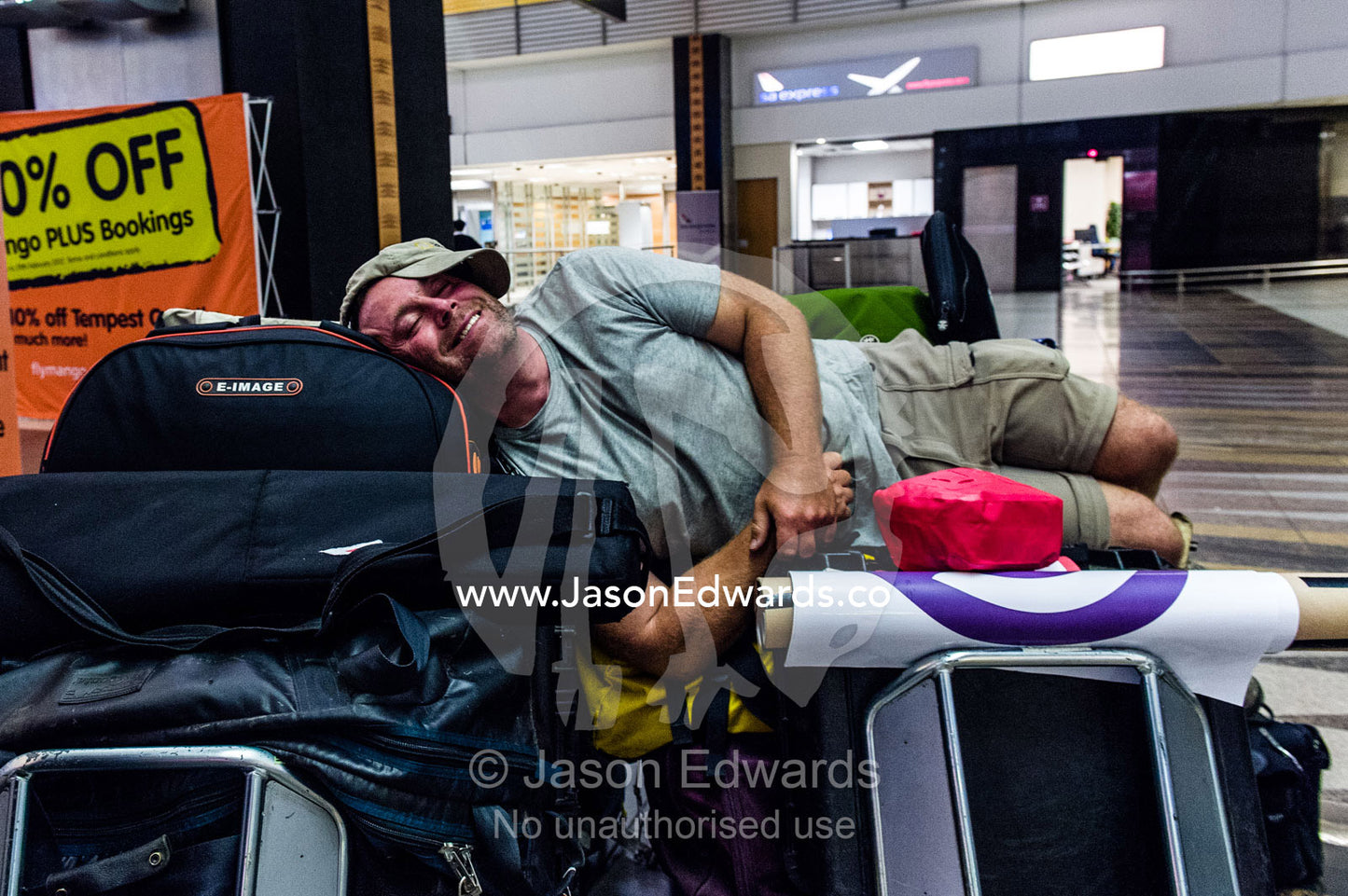 A photographer relaxes on his equipment after missing the last flight. Cape Town, Western Cape, South Africa.