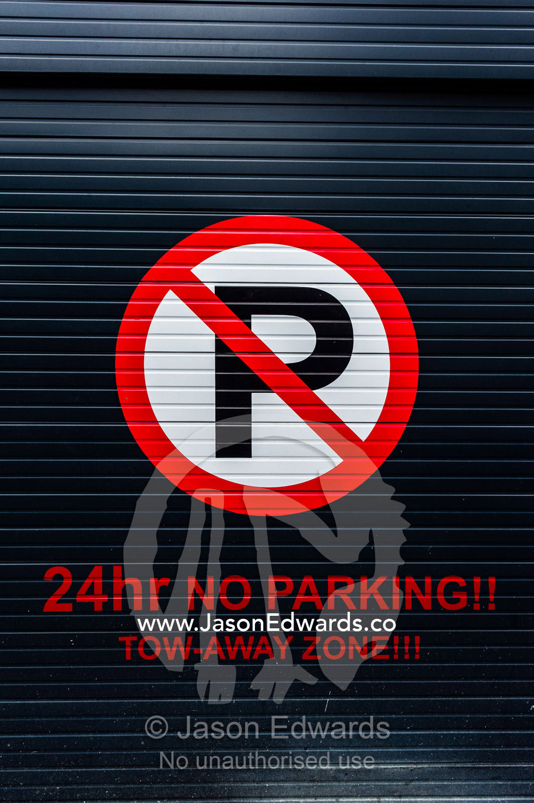 A sign on a garage door displays parking and access restrictions. Cape Town, Western Cape, South Africa.