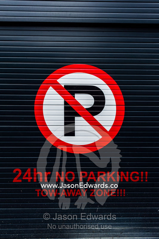 A sign on a garage door displays parking and access restrictions. Cape Town, Western Cape, South Africa.