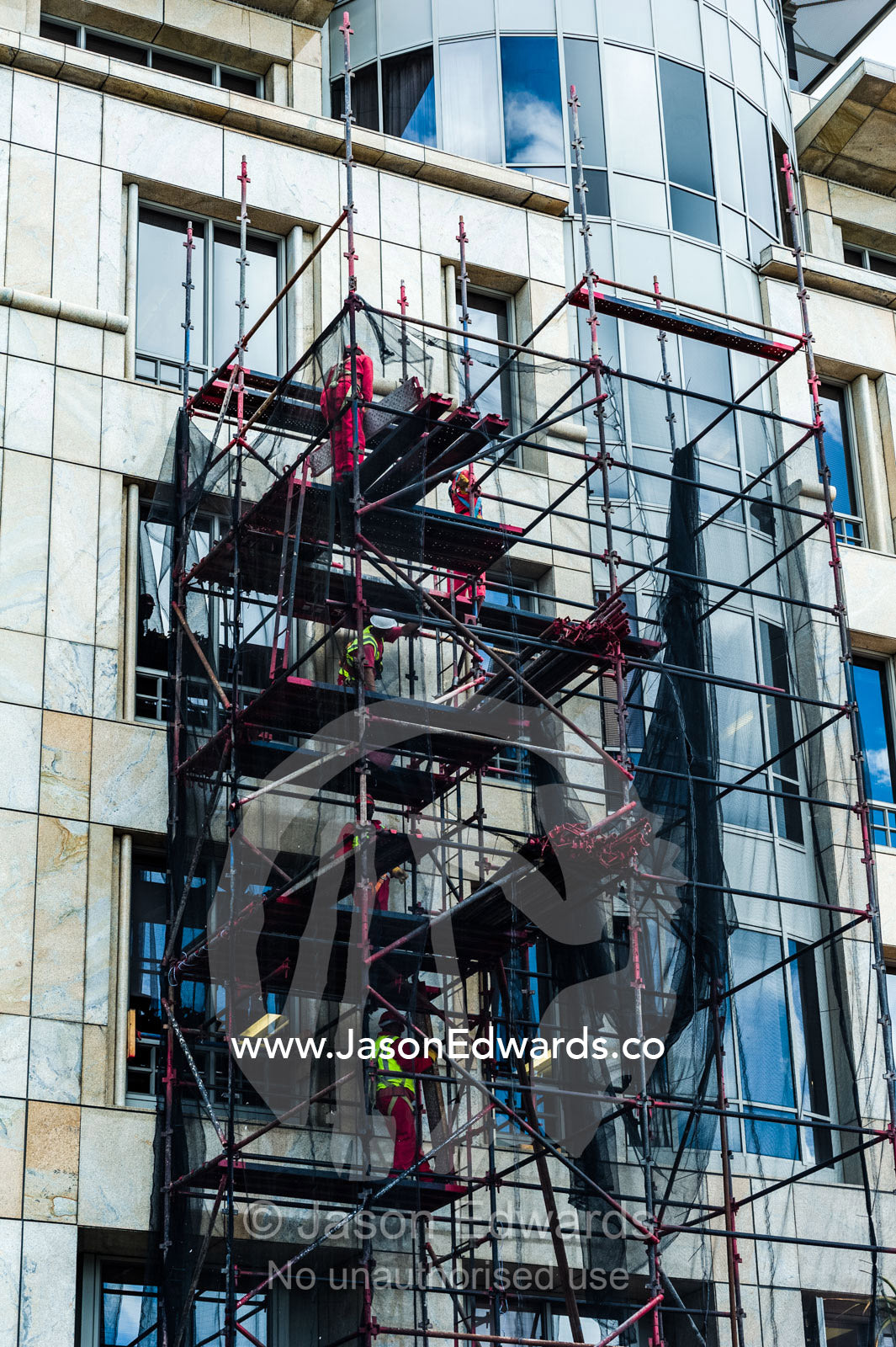 Scaffolding protects men working on high-rise apartment windows. Cape Town, Victoria and Alfred Waterfront, Western Cape, South Africa.