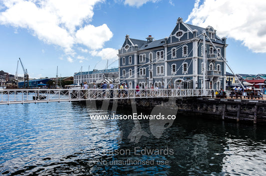 Pedestrians cross a bridge between wharves in a marina precinct. Cape Town, Victoria and Alfred Waterfront, Western Cape, South Africa.