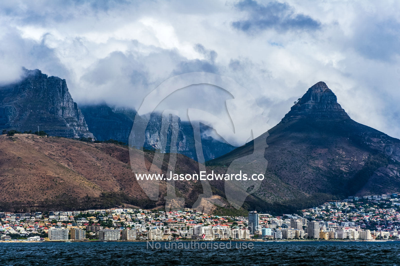 Rugged peaks emerge from menacing storm clouds over Cape Town. Table Mountain, Cape Town, Cape Peninsula, Western Cape, South Africa.