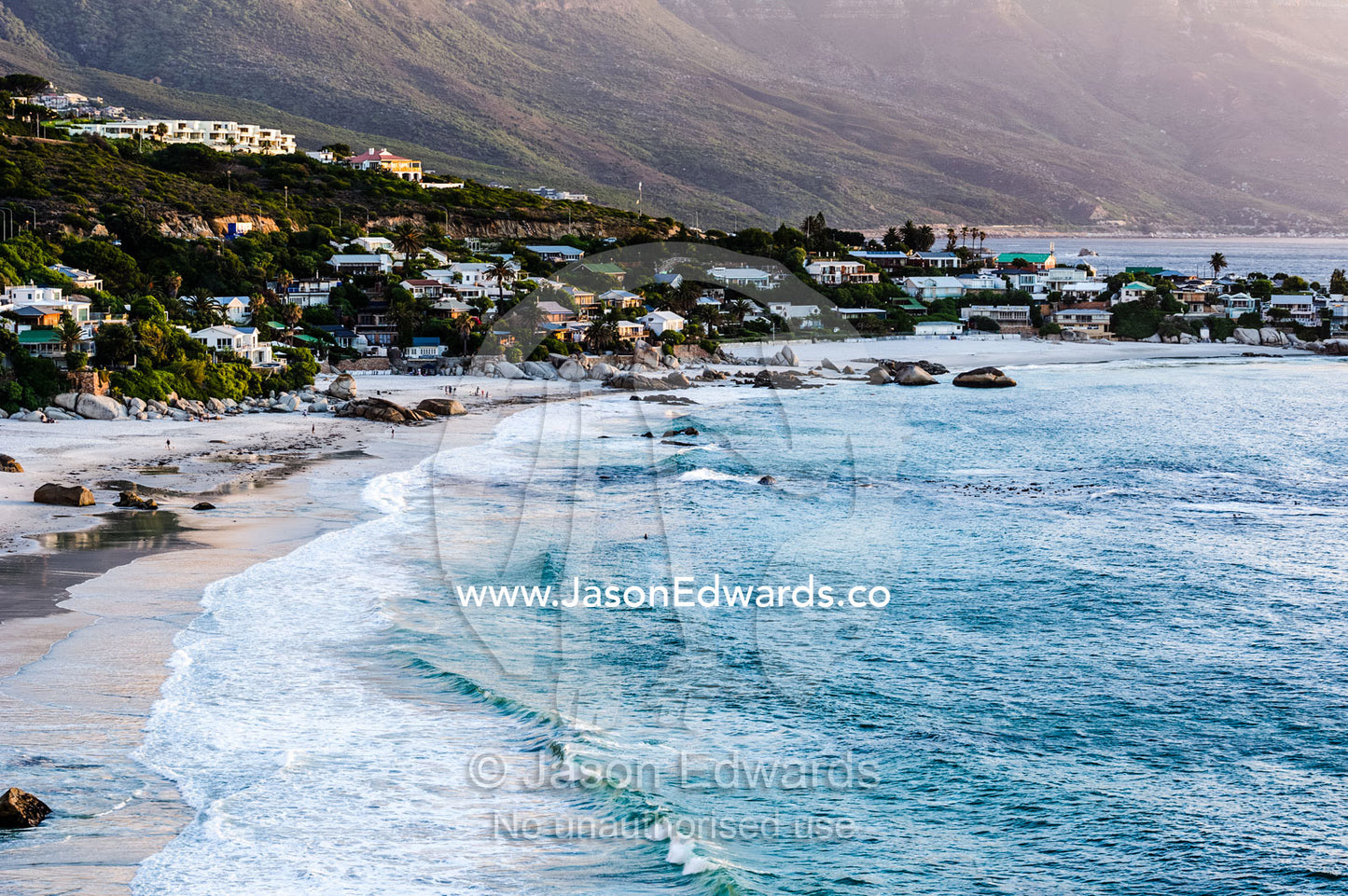 Beach houses nestled in rocky outcrops surrounding a small ocean bay. Clifton Beach, Cape Town, Western Cape, South Africa.