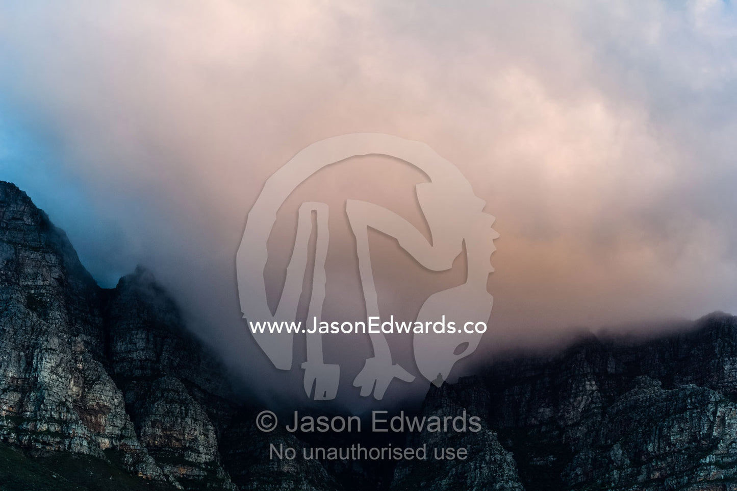 Ominous storm clouds descend on a jagged coastal mountain range. The Twelve Apostles, Chapmans Peak Mountain Range, Cape Town, Western Cape, South Africa.