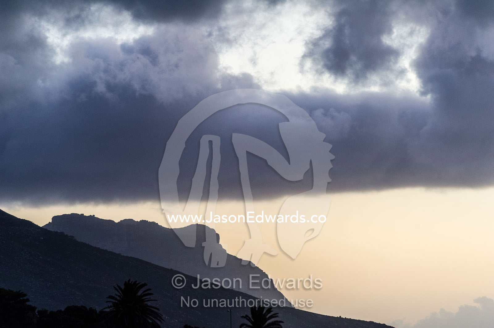 A storm front pushes a cloud bank down onto a mountain peak. Bantry Bay, Chapmans Peak Mountain Range, Cape Town, Western Cape, South Africa.