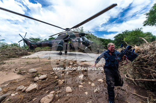 A cameraman runs from the downdraft of an airforce helicopter. Kruger National Park, South Africa.