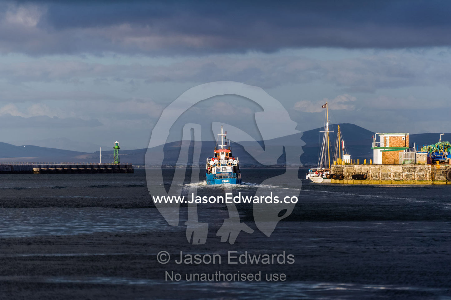 A commercial fishing trawler heads to sea from a harbor at sunset. Cape Town, Victoria and Alfred Waterfront, Western Cape, South Africa.
