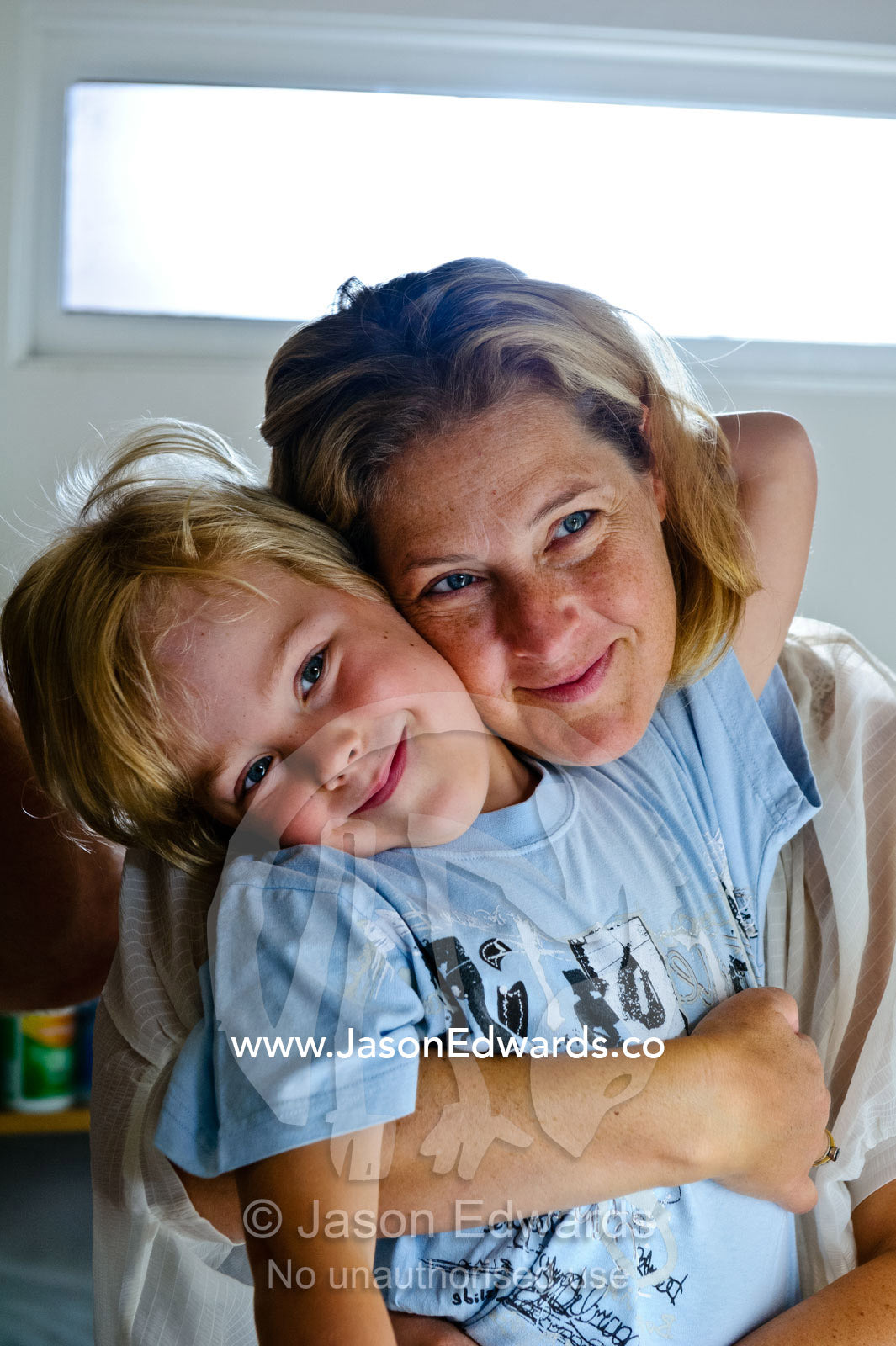 A mother hugs her son as he readies to attend his first day of school. Melbourne, Carlton North, Victoria, Australia.