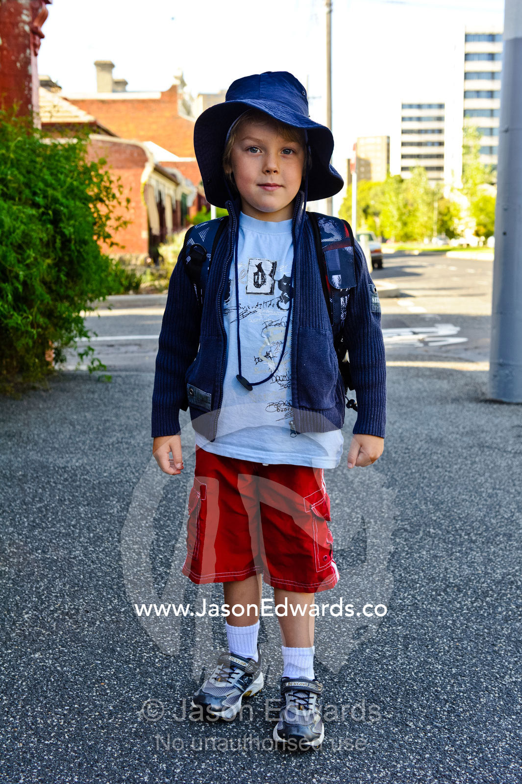 A boy poses for a picture outside his home on his first day of school. Melbourne, Carlton North, Victoria, Australia.