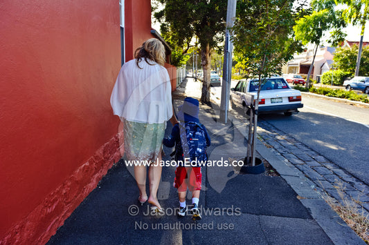 A mother walks with her son on his way to his first day of school. Melbourne, Carlton North, Victoria, Australia.