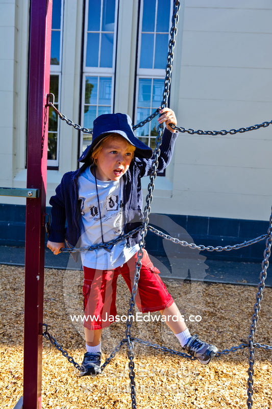 A boy explores the playground equipment on his first day of school. Carlton North, Melbourne, Victoria, Australia.