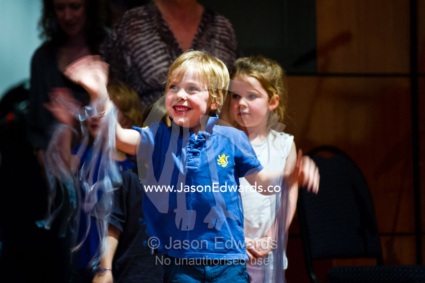 A boy waves to to his parents at a kindergarden school play. Kew, Melbourne, Victoria, Australia.