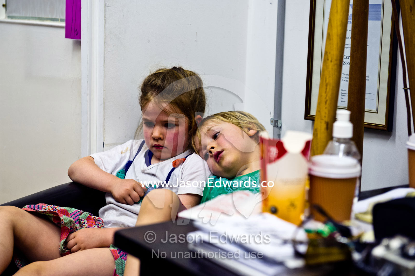 Two exhausted friends resting in an office armchair after school. Collingwood, Melbourne, Victoria, Australia.