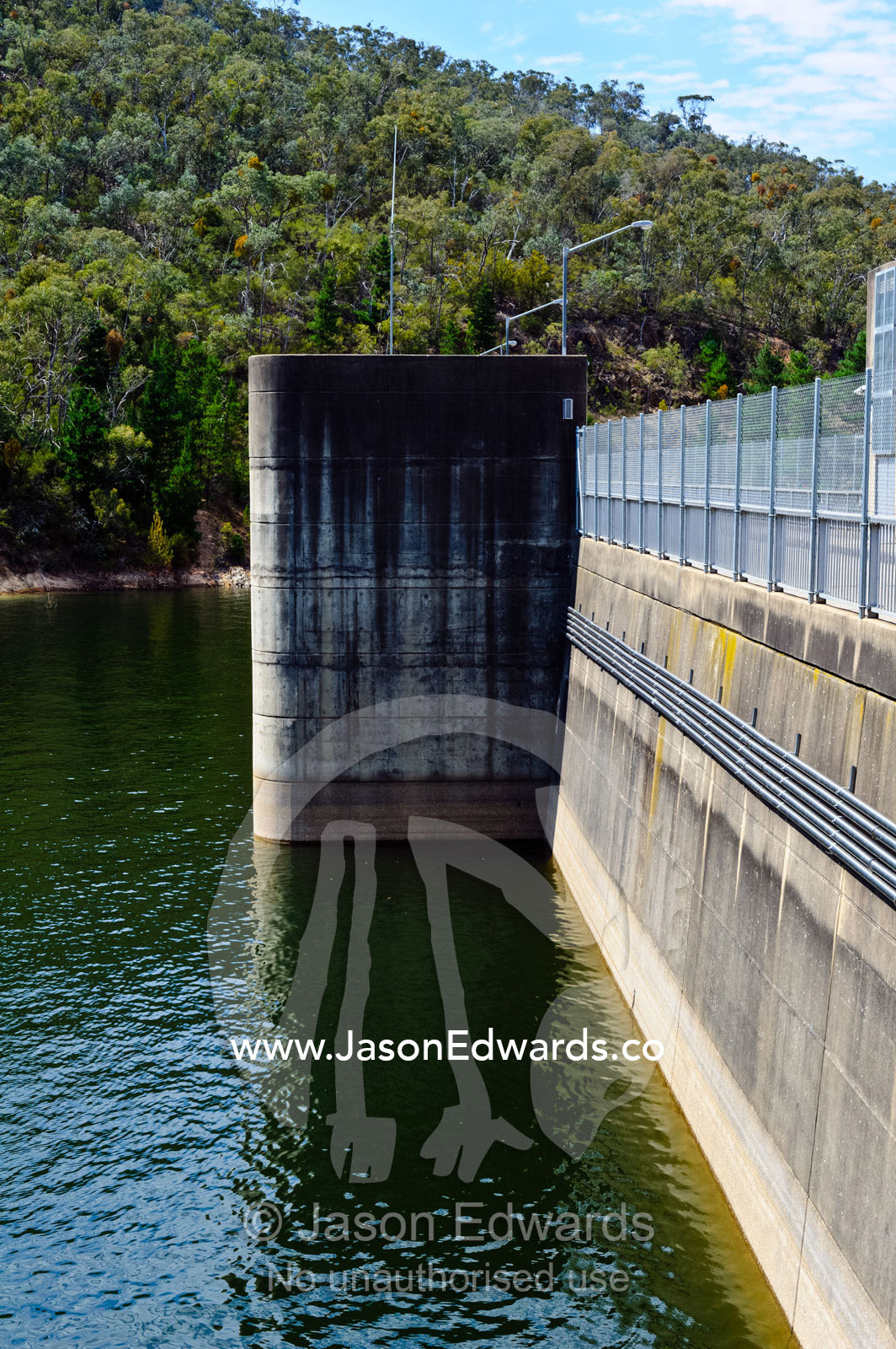 A city water catchment dam wall and spillway gates filled with water. Lake Eildon, Eildon Weir Spillway, Victoria, Australia.