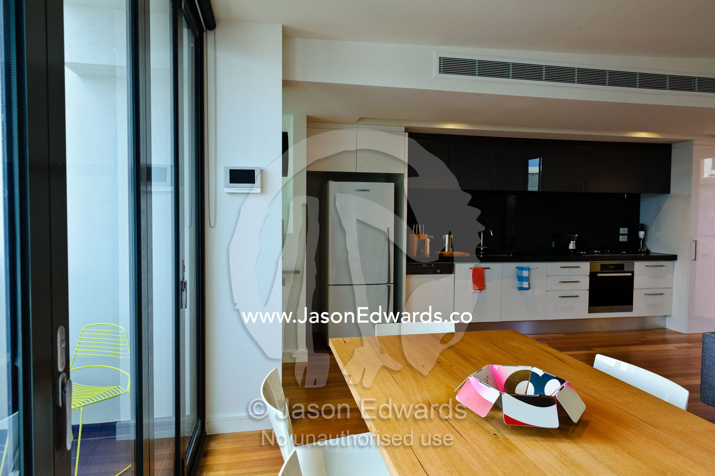 An open-plan dining table and kitchen area in an inner city apartment. North Melbourne, Melbourne, Victoria, Australia.