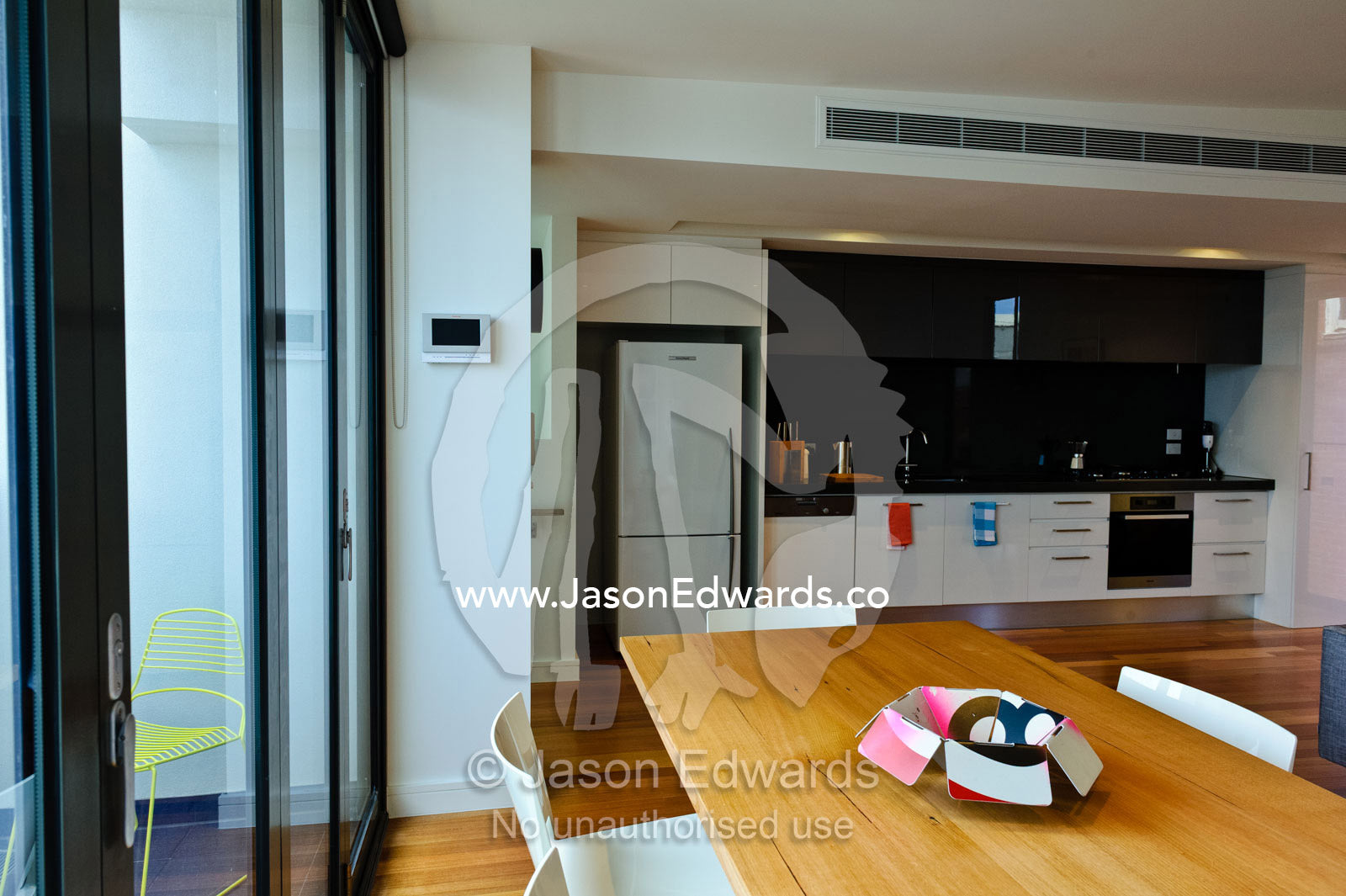 An open-plan dining table and kitchen area in an inner city apartment. North Melbourne, Melbourne, Victoria, Australia.
