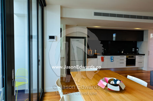 An open-plan dining table and kitchen area in an inner city apartment. North Melbourne, Melbourne, Victoria, Australia.