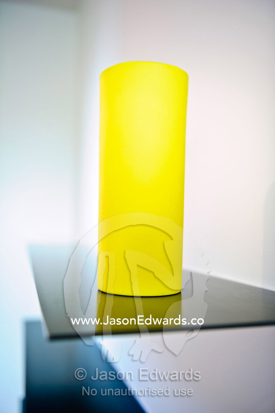 A canary yellow lamp on a stainless steel book shelf in an apartment. North Melbourne, Melbourne, Victoria, Australia.