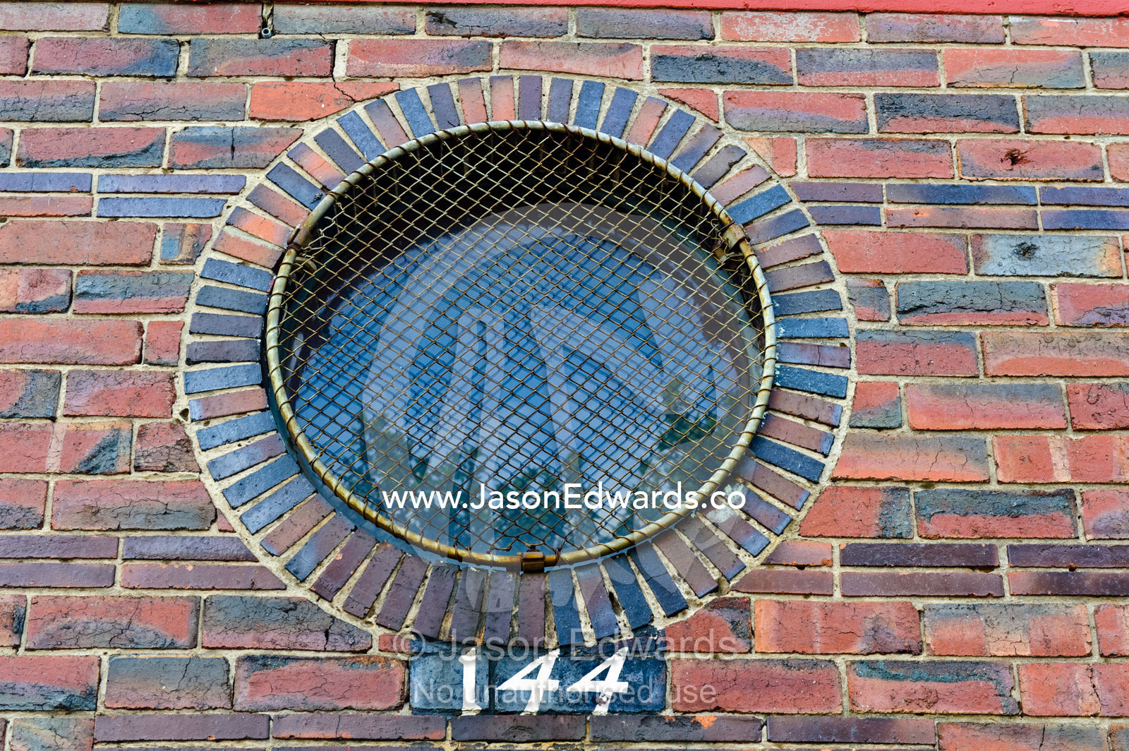 A circular brick window with a wire security screen over the glass. North Melbourne, Melbourne, Victoria, Australia.