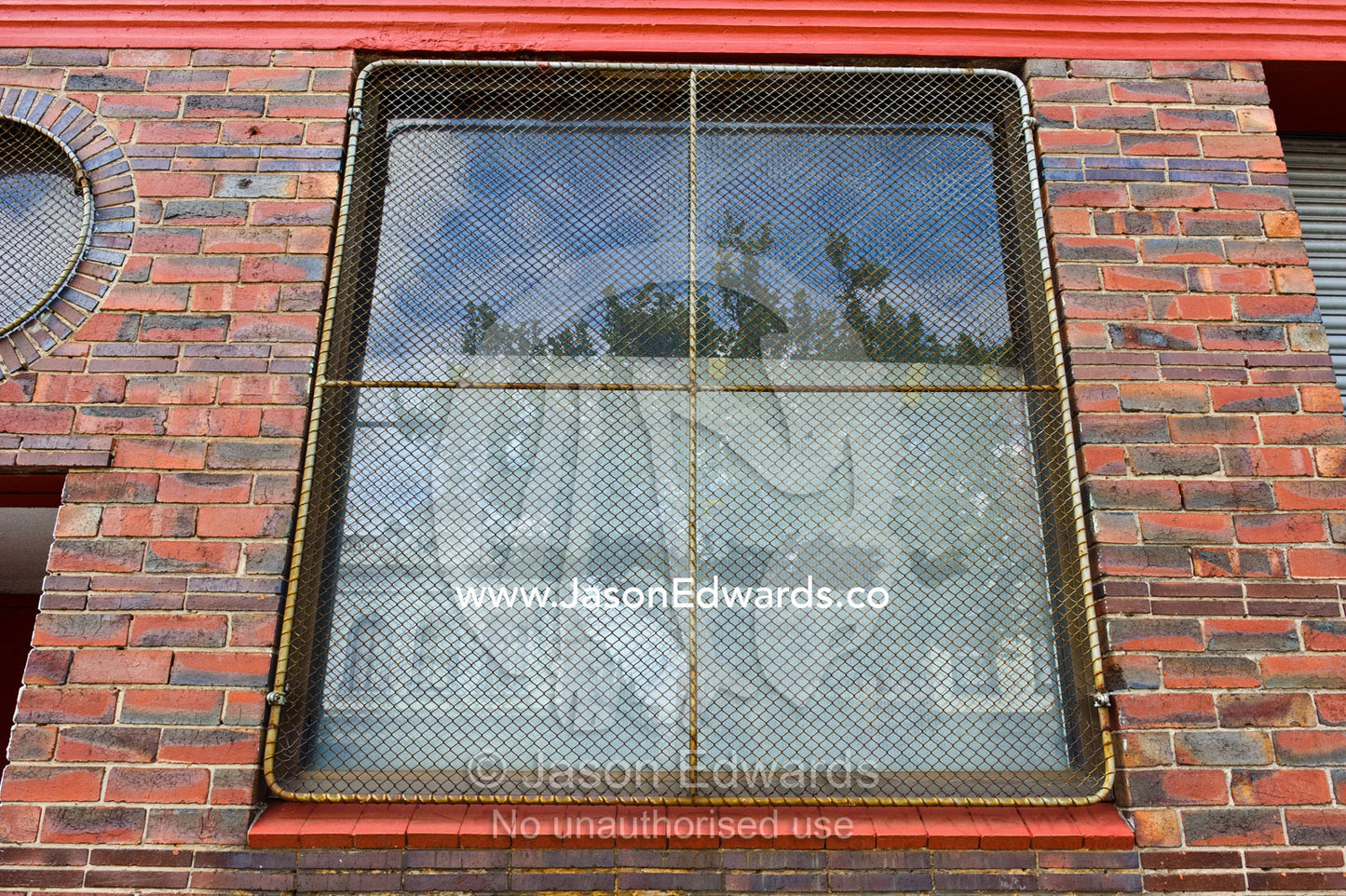 A square window in a red brick wall with a wire security screen. North Melbourne, Melbourne, Victoria, Australia.