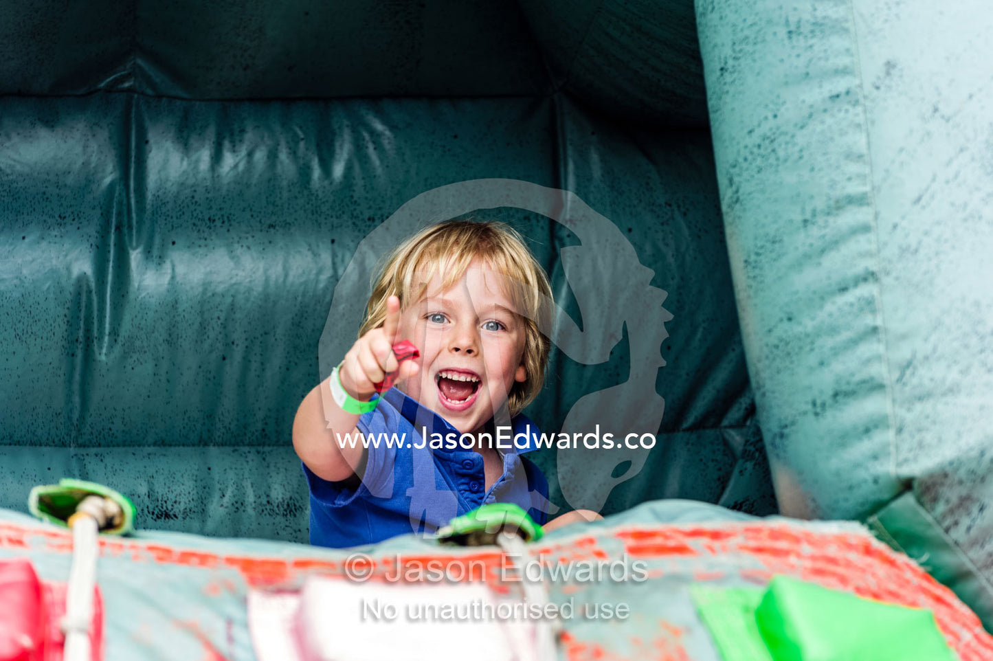 A boy laughing as he plays on an inflatable castle at a school fete. Carlton North, Melbourne, Victoria, Australia.