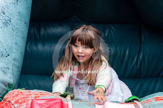 A girl laughing as he plays on an inflatable castle at a school fete. Carlton North, Melbourne, Victoria, Australia.