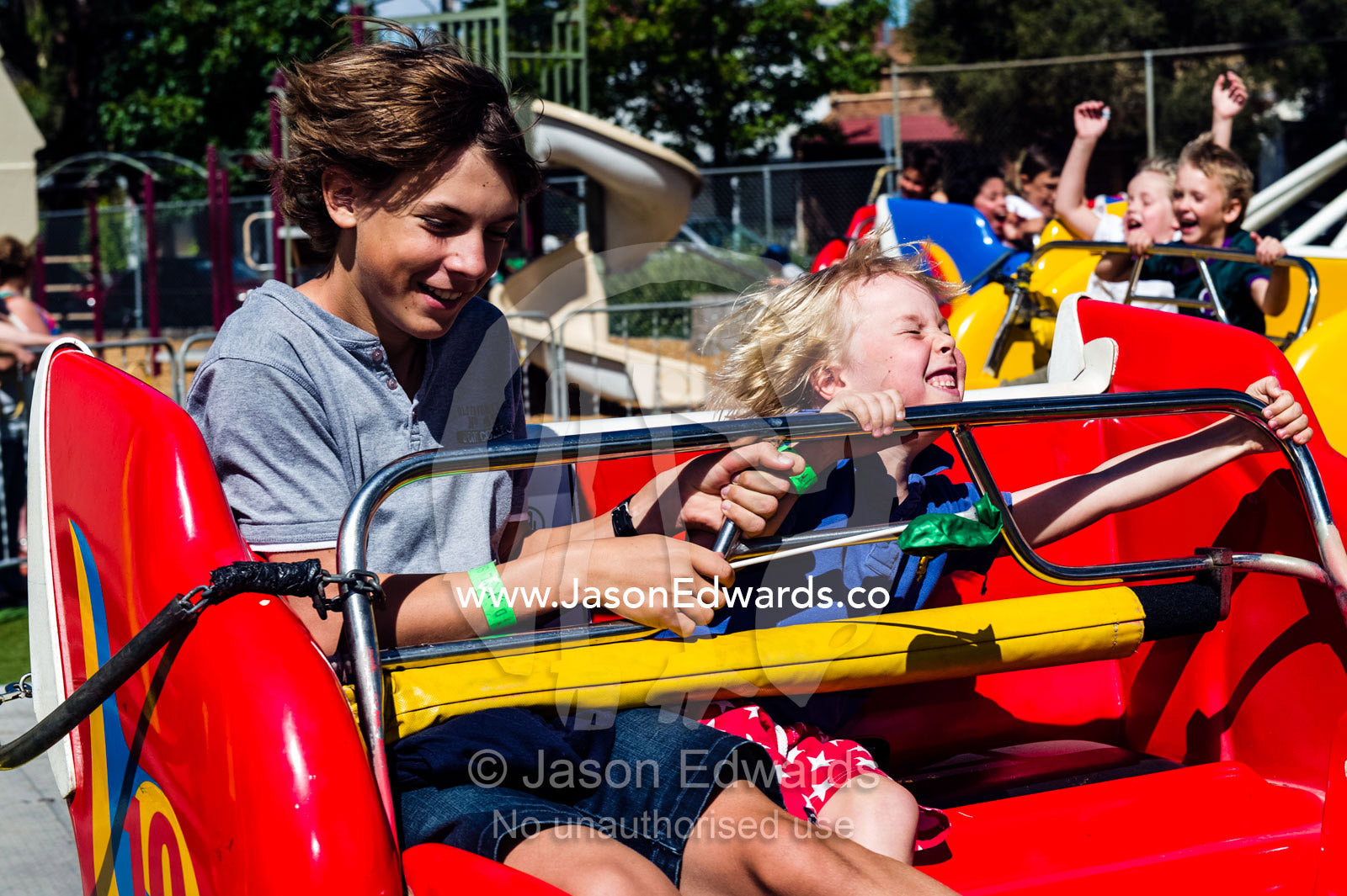 Friends laugh and struggle to hold on to a spinning ride at a fair. Lee Street Primary School, Carlton North, Melbourne, Victoria, Australia.