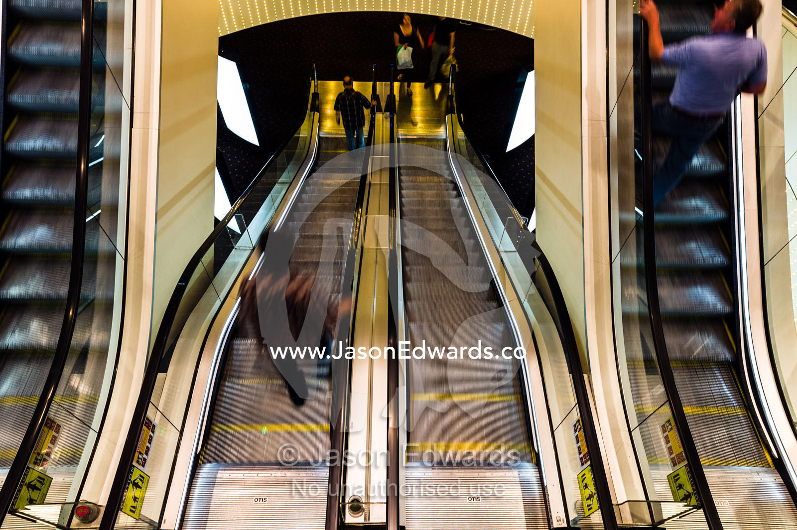 A stainless steel escalator descends between levels in a casino. Crown Casino, Southbank, Melbourne, Victoria, Australia.