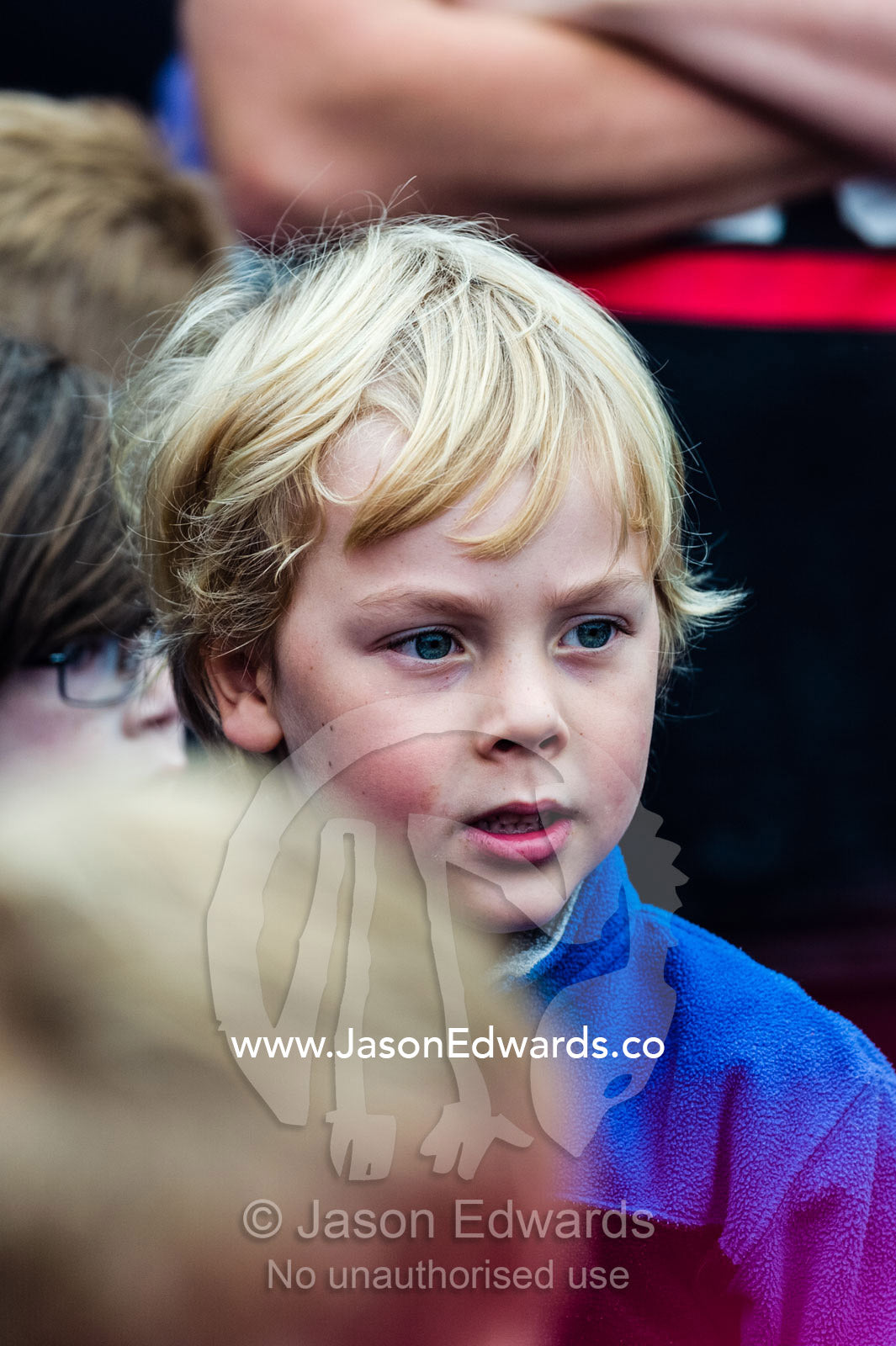A young boy stands in a crowd at a football training camp. Edinburgh Gardens, Fitzroy North, Melbourne, Victoria, Australia.