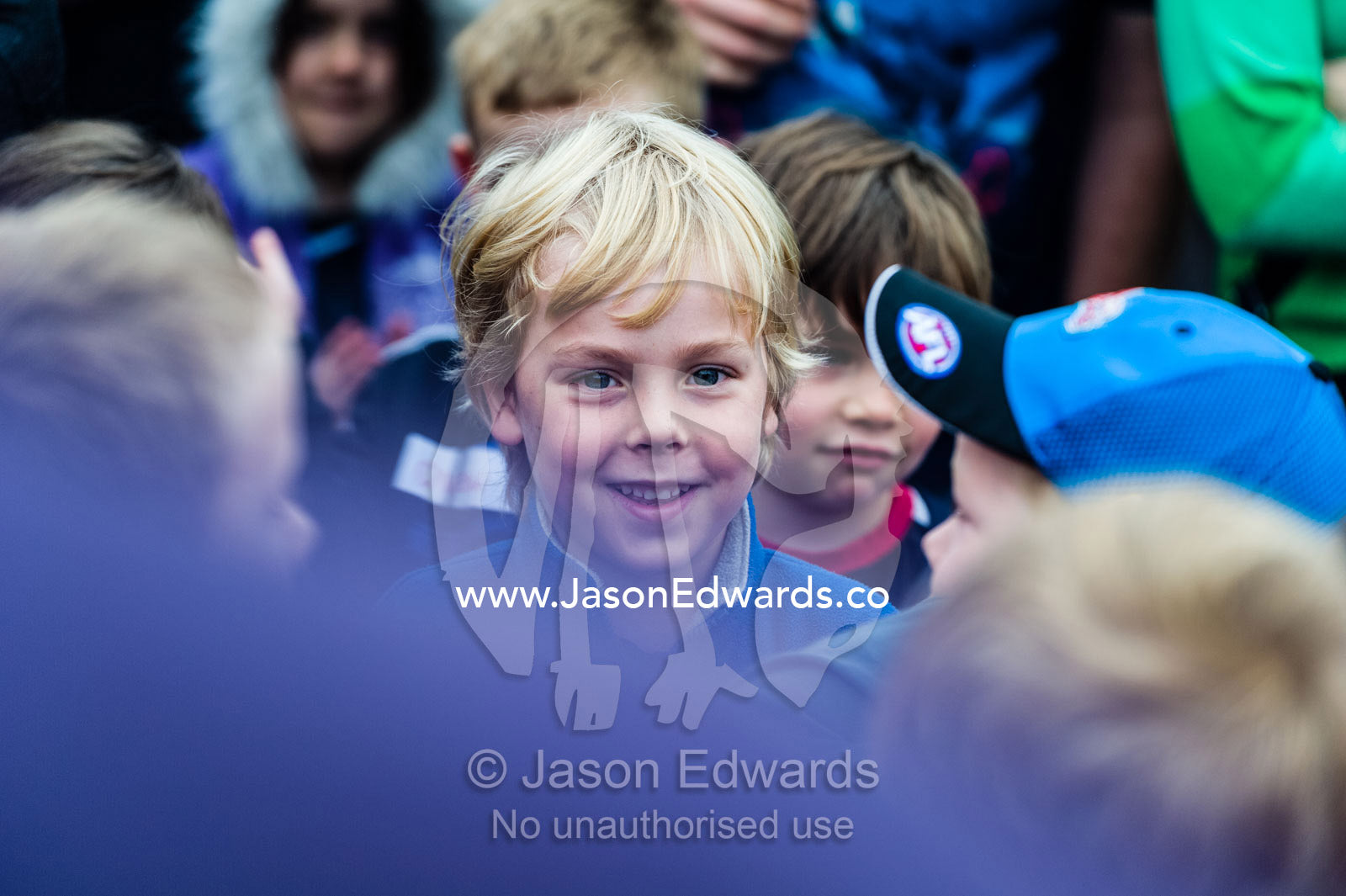 An excited young boy stands in a crowd at a football training camp. Melbourne , Edinburgh Gardens, Fitzroy North , Victoria , Australia
