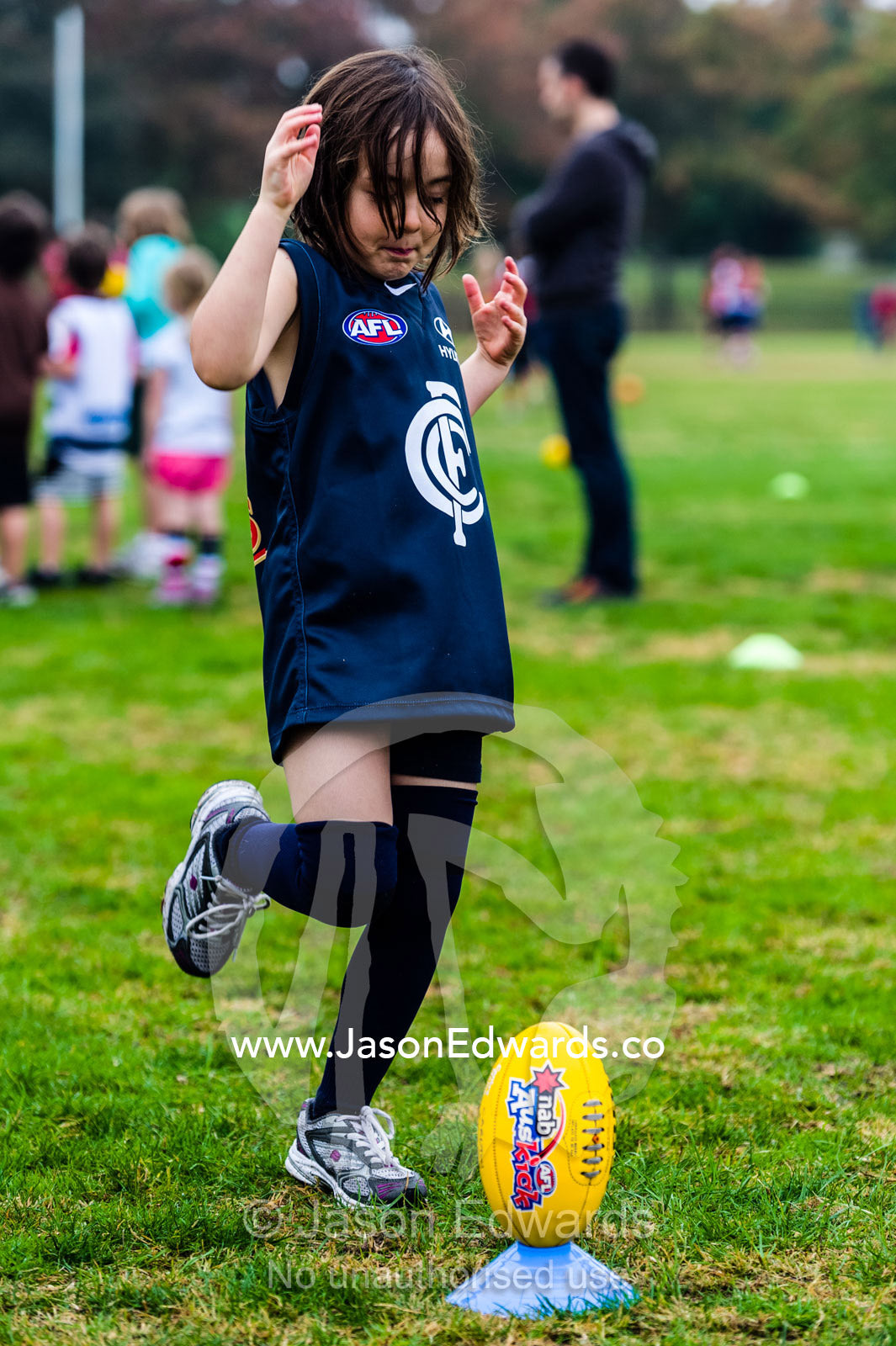 A girl practices kicking a football at a training camp. Edinburgh Gardens, Fitzroy North, Melbourne, Victoria, Australia.