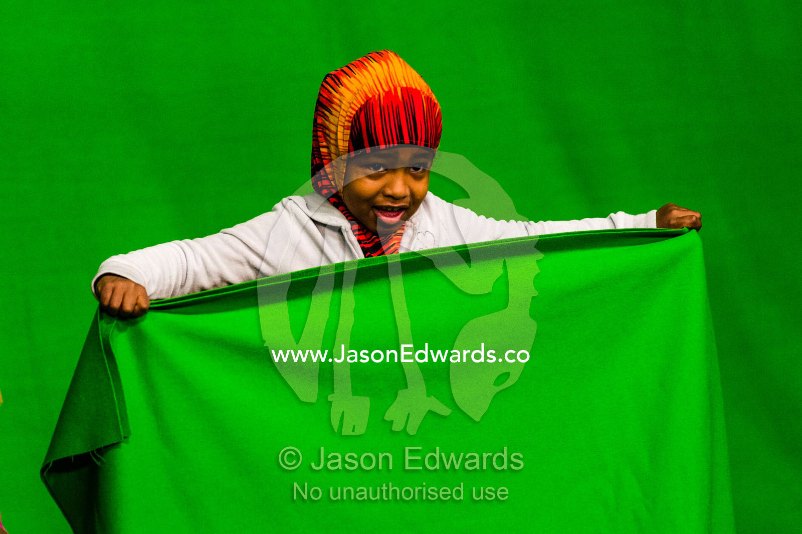 A schoolgirl holds a green screen curtain in front of her at a studio. Victoria, Melbourne, Australia.