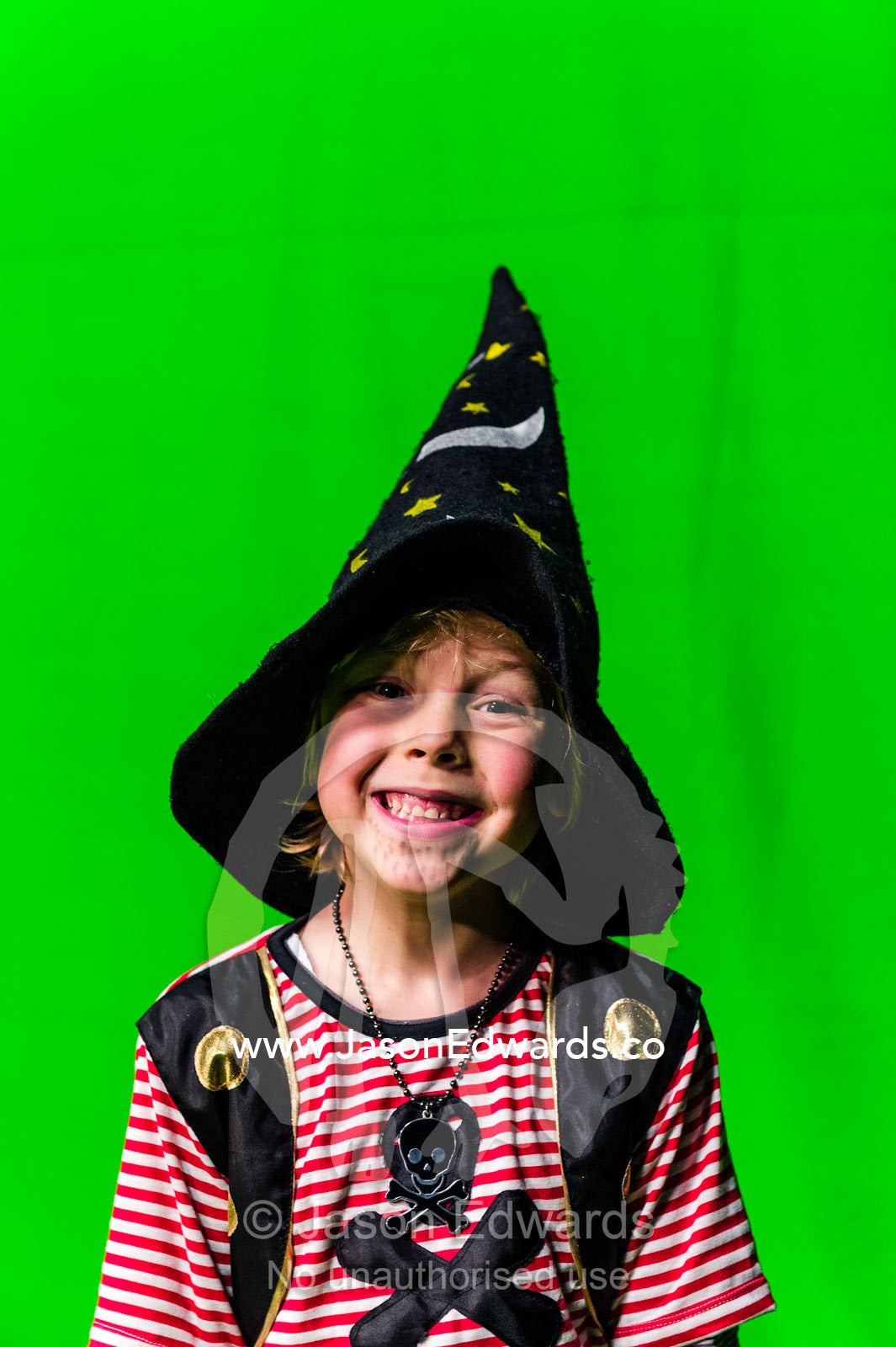 A boy dressed as a pirate in a witches hat in front of a green screen. Victoria, Melbourne, Australia.