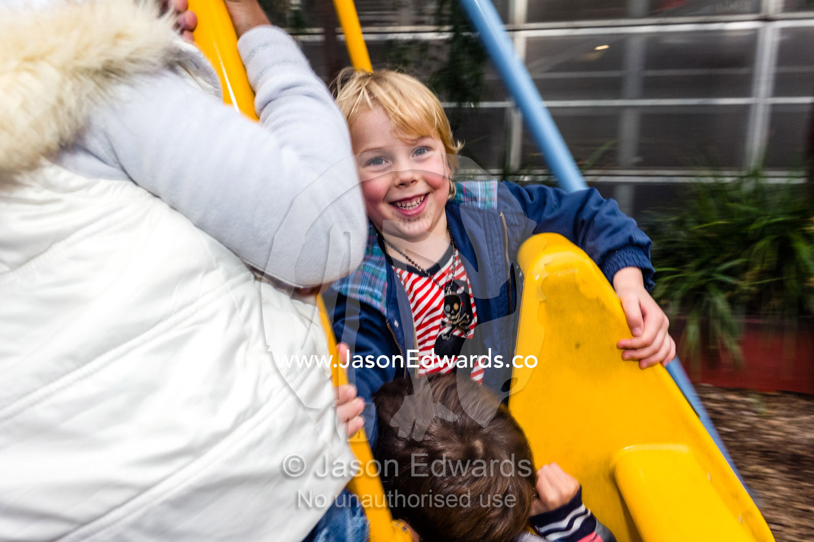 A schoolboy laughing as he soars on a swing in a playground. Birrarung Marr Park, Federation square, Melbourne, Victoria, Australia.